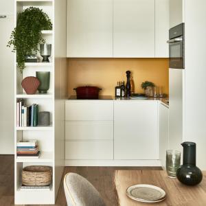 a kitchen with white cabinets and a wooden table at Falkensteiner Residences Jesolo in Lido di Jesolo