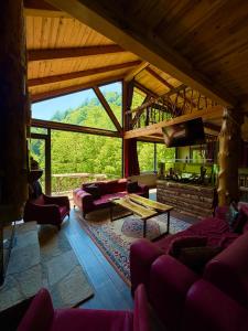 a living room with purple furniture and a large window at Riona dağ evleri in Çamlıhemşin