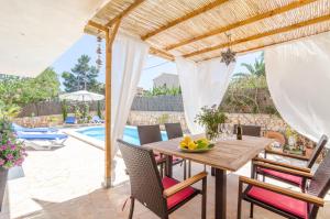 un patio con tavolo e sedie in legno e una piscina di Xalet S'Escaleta a Cala Santanyi