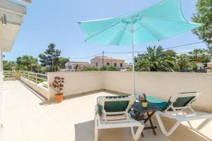 a patio with two chairs and a table with an umbrella at Xalet S'Escaleta in Cala Santanyi