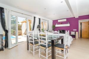 a dining room with a glass table and purple walls at Xalet S'Escaleta in Cala Santanyi