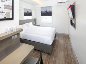 a bedroom with a white bed and a desk with a bed at Red Planet BGC The Fort in Manila +44 photos