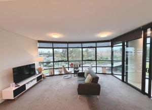 a living room with a couch and a television at Floor-to-Ceiling Park View Oasis at Olympic Park Free Parking Sleeps 5 in Sydney