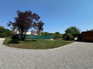 a gravel driveway with a tree in the middle at Casale Rûsignul in Cassegliano