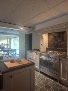a large kitchen with a stove and a table at De Flamberthoeve in Ieper