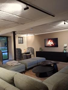 a living room with couches and a tv on the wall at De Flamberthoeve in Ieper