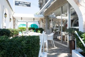 a restaurant with white chairs and tables on a patio at Le Village Hotel in Limassol