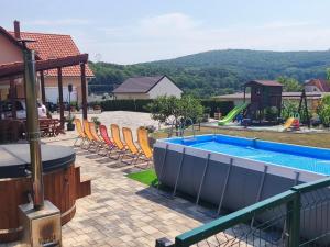 a swimming pool with chairs and a playground at Eplényi Apartmanház in Eplény