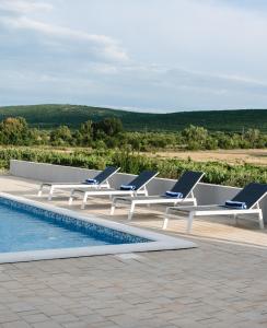 a row of lounge chairs next to a swimming pool at Villa Bagulina in Drniš