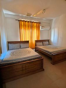 two beds in a room with orange curtains at Ocean Breeze Apartment Colombo in Colombo