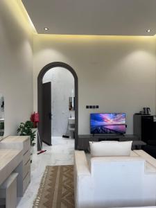 a living room with a couch and a tv on the wall at شقق ميلا الباحة الفاخرة in Al Baha
