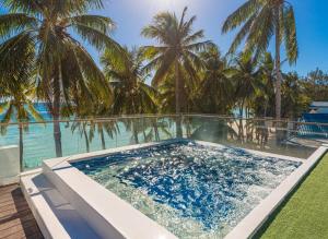 a swimming pool with palm trees and the ocean at The Muse Hotel Boracay in Boracay