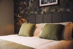 a bedroom with a bed with two green pillows at George & Dragon Hotel in Kirkbymoorside +51 photos