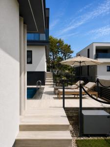 a patio with benches and an umbrella next to a building at Villa VELUNA Liznjan Residence in Ližnjan