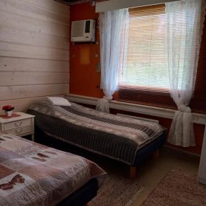 a bedroom with two beds and a window with a tv at LappHouse Puistola in Palojoensuu