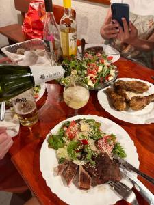 a table with plates of food and a bottle of wine at Orpheus Hotel in Varna City
