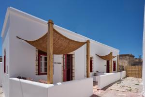 a white building with a large umbrella on it at Oikia Pouloudi in Kimolos