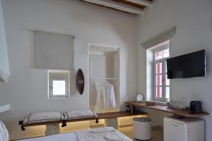 a white room with a bed and a table and a tv at Oikia Pouloudi in Kimolos