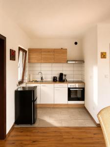 a kitchen with white cabinets and a black refrigerator at Ferienwohnung Maison Maurus nahe Idar-Oberstein in Mörschied