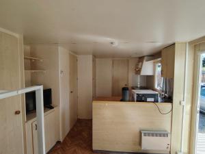a small kitchen with wooden cabinets and a microwave at Camping Les Embruns N2 in Le Grau-dʼAgde