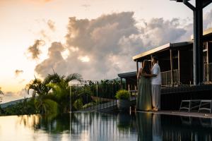a bride and groom standing next to a swimming pool at Hôtel Diana Dea Lodge & SPA in Sainte-Anne-les Hauts