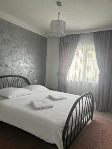 a bedroom with a bed with white sheets and a window at Borșa ApartHotel 4 in Borşa