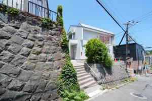 a stone wall next to a white house at plus81 OTARU Entire House 9min Walk from Minami Otaru Station in Otaru