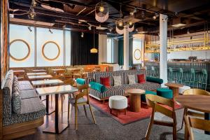 a restaurant with couches and tables and chairs at Aloft by Marriott Munich in Munich