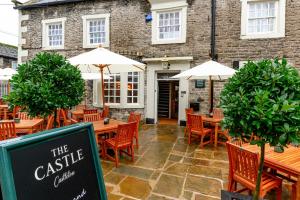 a restaurant with wooden tables and chairs and umbrellas at The Castle by Innkeeper's Collection in Castleton