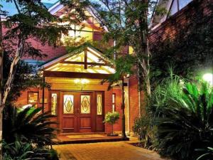 a brick house with a wooden door with a porch at The Woodpecker Inn in Pretoria
