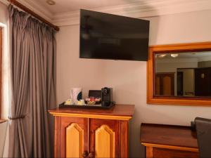 a room with a television on a wall with a cabinet at The Woodpecker Inn in Pretoria