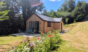 a wooden shed with a table and chairs in a garden at Yr Hen Stabl - The Old Stable in Llangerniew