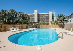a swimming pool with chairs and a building in the background at Wind Drift South East 404 in Orange Beach