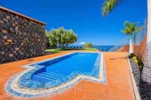 a swimming pool in front of a house with a wall at LAS MORADITAS, CHALET con PISCINA PRIVADA in Adeje
