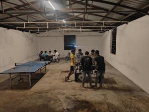 a group of people standing around a ping pong table at Rock Retreat in Kanakapura