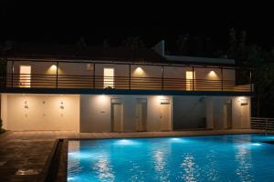 a house with a swimming pool at night at Rock Retreat in Kanakapura