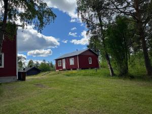 a red barn sitting on top of a lush green field at NorrskensRo in Kiruna