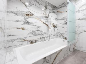 a bathroom with a white tub and marble walls at Hotelikum zentreal Bequem in Heilbronn +169 photos