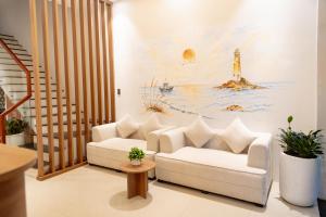 a living room with a white couch and a painting of a lighthouse at Dorm Beachside Hotel & Hostel By Haviland in Danang