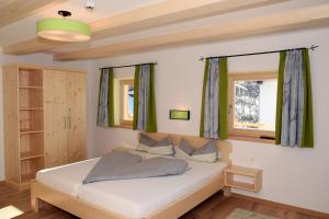 a bedroom with a white bed and two windows at Hotel Biobauernhof Hinteraltensberg Wildschönau in Auffach
