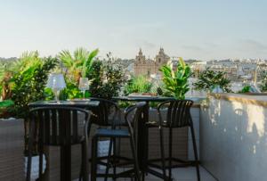 a balcony with two tables and chairs with a view of a city at Royale Sainte Hélène Boutique Hotel in Birkirkara +48 photos