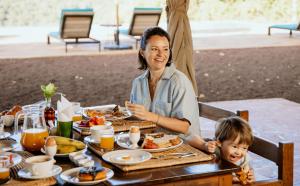a woman and a child sitting at a table eating food at Pembeni Rhotia in Karatu