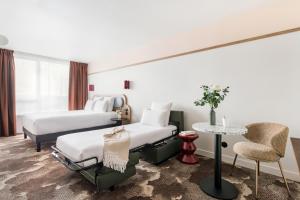 a hotel room with two beds and a table at Kyriad Lyon Est Stadium Eurexpo Meyzieu in Meyzieu