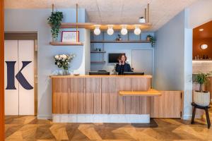 a woman sitting at a reception desk in an office at Kyriad Lyon Est Stadium Eurexpo Meyzieu in Meyzieu