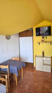 a yellow room with a table and a tv at Apartments Sijerkovic in Herceg-Novi