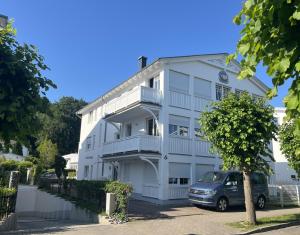 a white building with a car parked in front of it at Villa Hansa Binz App 4 am Kurpark Meine Ferienzeit in Binz