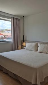 a bedroom with a large white bed with a window at Hotel El Cruce Moraleda in Moraleda de Zafayona