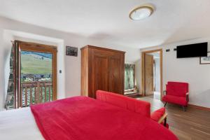 a bedroom with a red bed and a balcony at Locanda delle Miniere in Ollomont