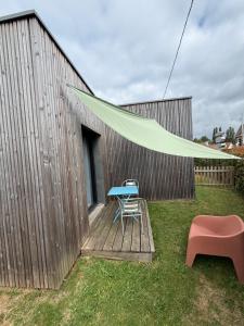 a table and a chair on a deck with a tent at L'Orée du Golf, studio 2 in Mont-Saint-Aignan