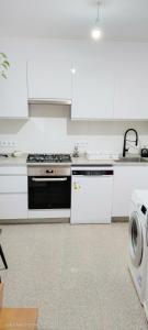 a white kitchen with a stove and a dishwasher at La Chungita in Villanueva de Arosa